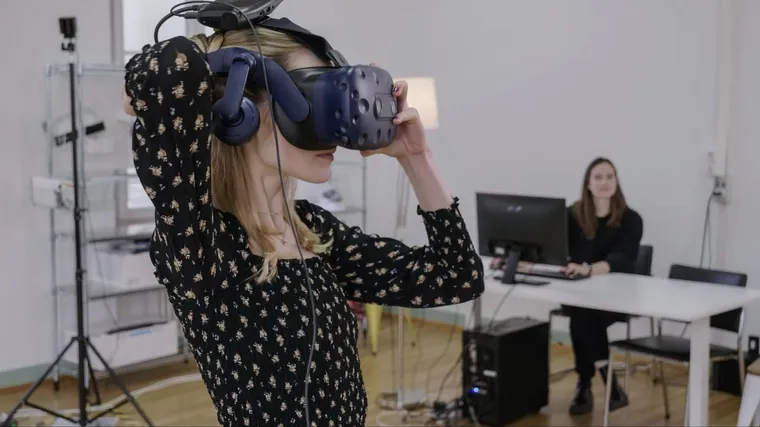 An operator assists a user wearing a VR headset during a ViRTUE training session